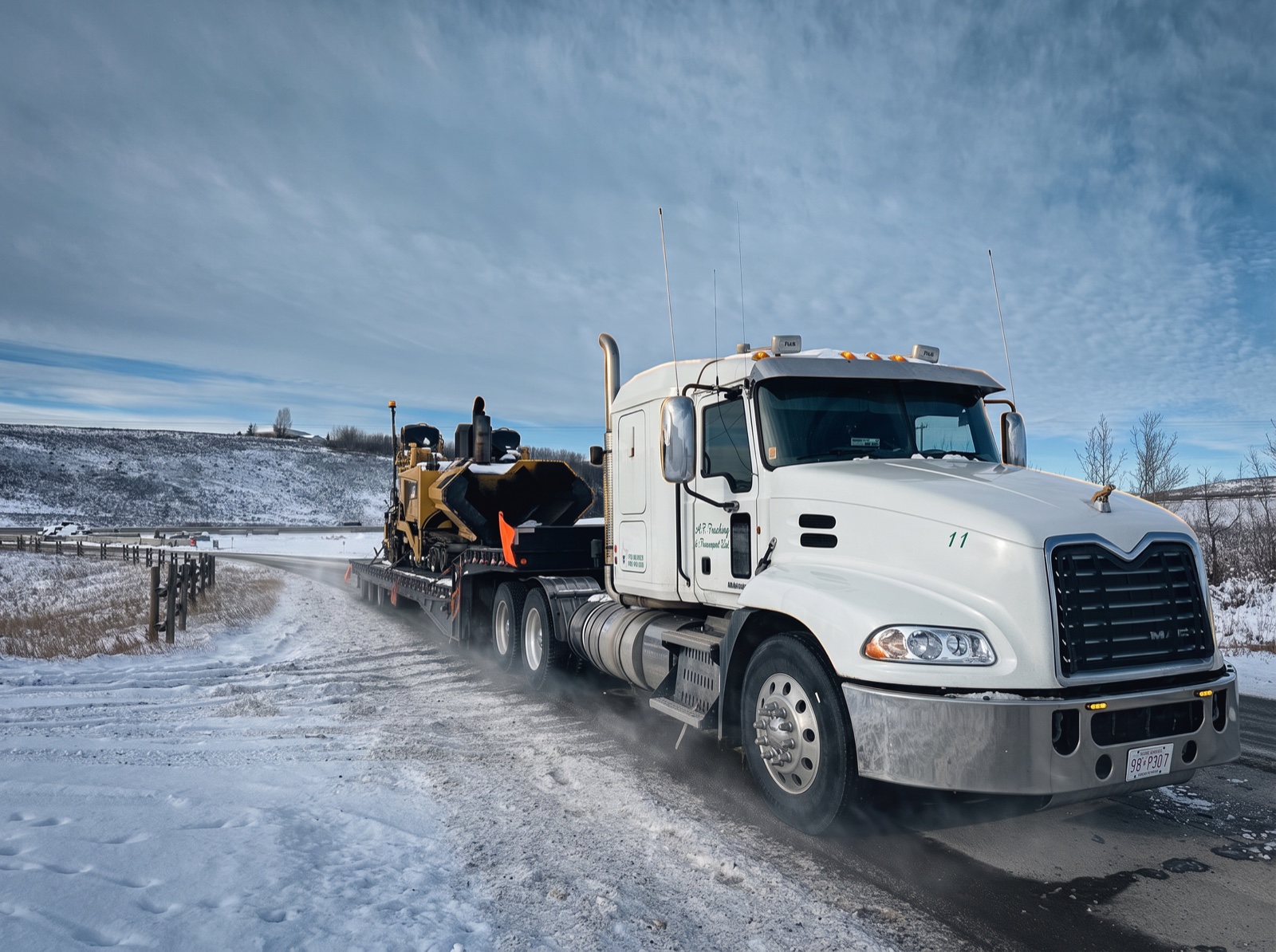 A.F. Trucking & Transport white Mack tractor hauling a CAT paver on a winter Alberta highway