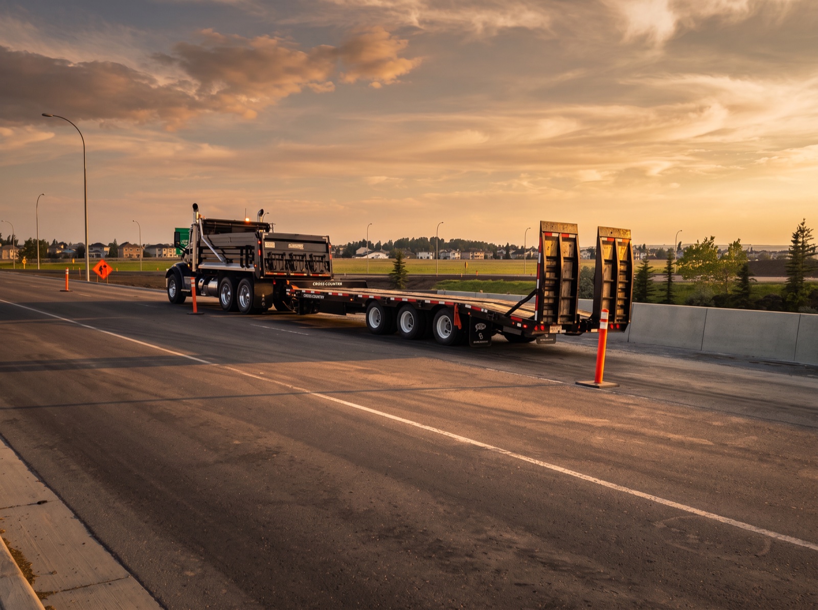 A.F. Trucking tandem dump truck pulling an empty tri-axle step-deck trailer with its beavertail ramps upright